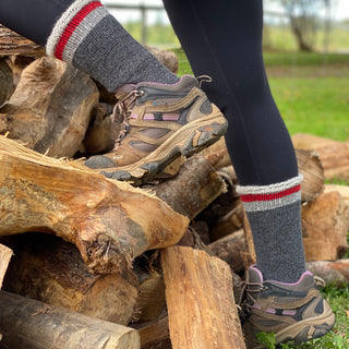 The shoes and alpaca socks of someone climbing a wood pile