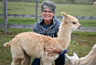 Janet posing with a young alpaca.