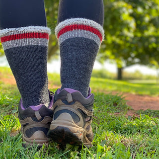close up view of a hikers shoes and socks walking across green grass